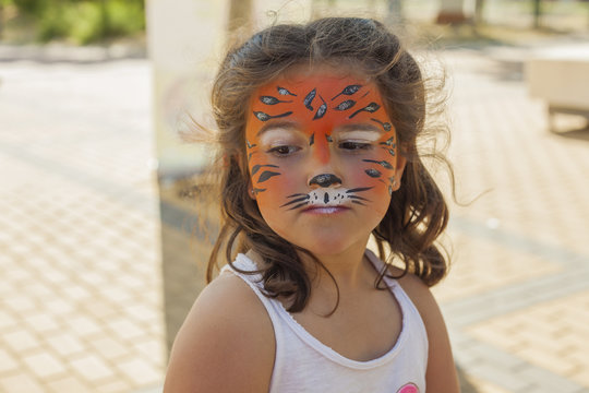 Little girl with her face painted like a tiger