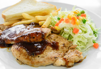 Grilled pork steak fillet with salad and French fries on white plate