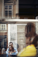A reflection of a man hugging a woman in a window of the cafe