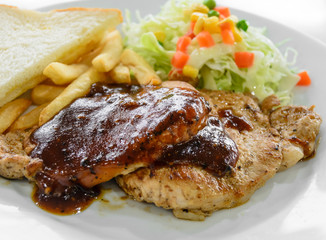 Grilled pork steak fillet with salad and French fries on white p
