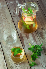 Two glass and carafe of green tea with mint and apples