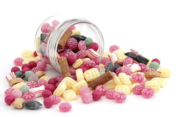 Many colored candy falling out of a jar