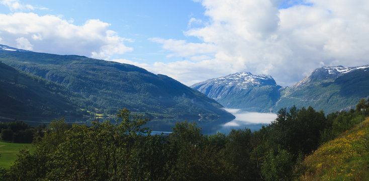 Classic norwegian scandinavian summer mountain landscape view with mountains, fjord, lake with a blue sky, Norway