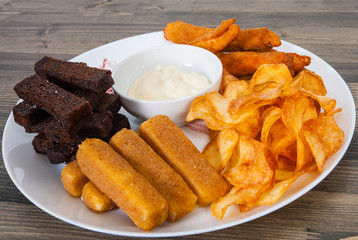 dish with different snack to beer on wooden table