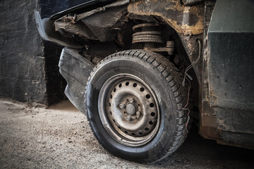 Fototapeta na wymiar Abandoned rusted car fragment with wheel