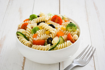Pasta salad in a bowl on white wooden table

