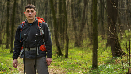 Hiker wearing hiking backpack and jacket on hike in forest.