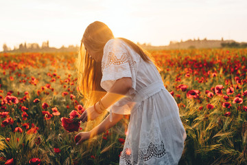 Fototapeta na wymiar young caucasian female in poppy field enjoying the sunset