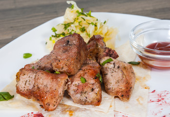 Shashlik. pieces of grilled meat with salad on a plate