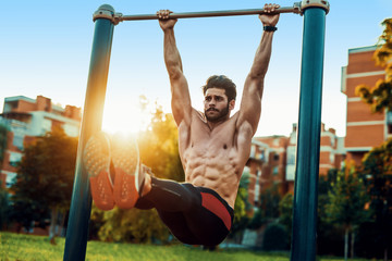 Young man exercising on horizontal bar outdoors