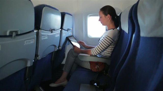 Woman uses tablet computer touchscreen in the plane