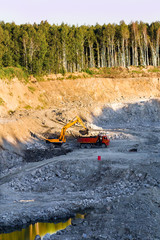 Excavator in a quarry loads rocky ground in the truck