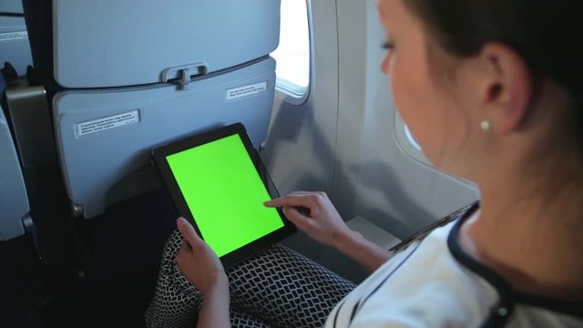 Woman uses green screen tablet computer touchscreen in the plane