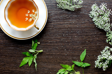 herbal saxifrage pimpinella tea in a porcelain cup on a dark wooden background