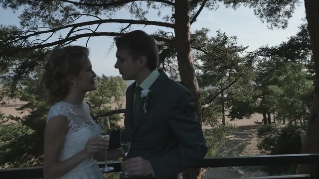 the couple in the shade of the trees on the terrace, kissing with champagne glasses