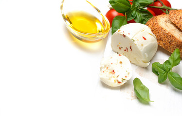 Delicious cheese mozzarella, tomato and basil leaves in white plate over white background