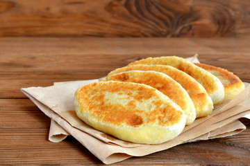 Deep fried pies on paper and wooden table. Hand pies cooked from unleavened dough. Home cooking