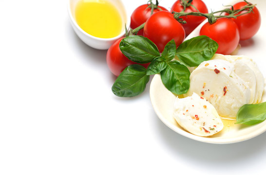 Delicious cheese mozzarella, tomato and basil leaves in white plate over white background