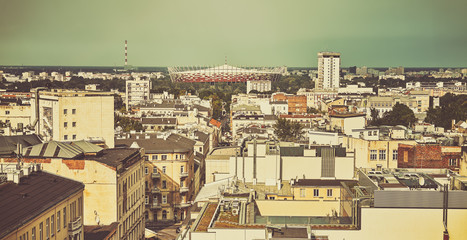 Old film retro stylized Warsaw skyline with roofs and stadium in a distance.