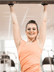 Sexy athletic sport smiling girl with fitness shape body posing and relaxing in the gym