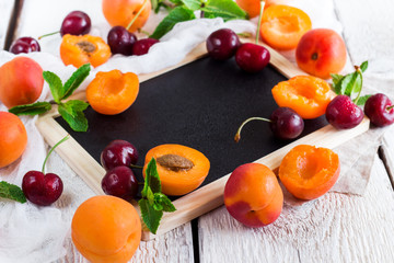 Black board with organic ripe apricots and cherries
