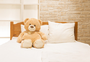 Teddy bear toy sitting alone on the white bed