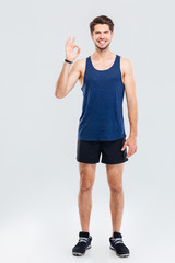 Obraz premium Full length portrait of a fitness man showing okay sign