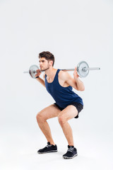 Handsome young man athlete doing squats with barbell