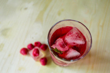 homemade refreshing summer cocktail with ice, fresh berries raspberry on wooden cutting Board