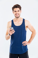 Happy young sportsman standing and using smartphone