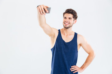 Fototapeta premium Happy young man athlete making selfie using mobile phone
