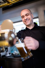 Brewer filling beer in beer glass from beer pump