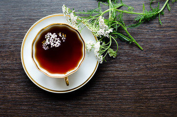 herbal yarrow tea in a porcelain cup on a dark wooden background