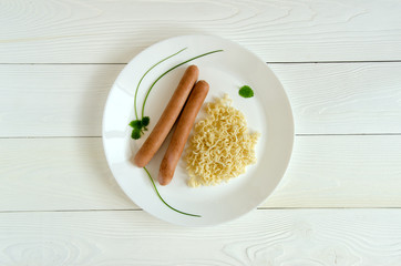 Two sausages white plate noodles top view