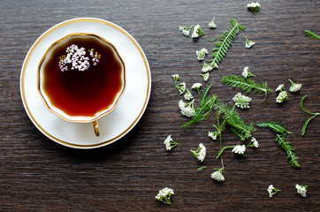 herbal yarrow tea in a porcelain cup on a dark wooden background © semenova_masha
