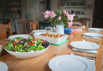 Dinner table setting with salad and food ready to serve and eat.