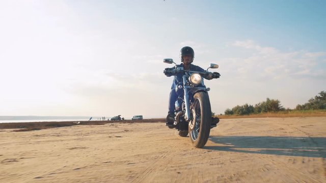 Motorcyclist driving his motorbike on the road during sunset near the water