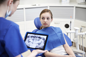 Fototapeta premium dentist showing x-ray on tablet pc to patient girl