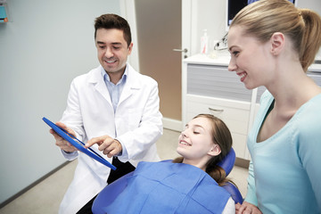 Fototapeta premium dentist showing tablet pc to girl and her mother
