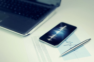 close up of smartphone, laptop and pen on table