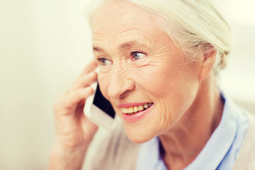 senior woman with smartphone calling at home