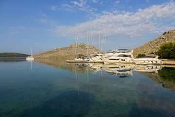 Obraz premium Luxury Yachts mored, colored sunset in a small bay in national parLuxury Yachts mored in colored sunset in a small bay in national park Kornati.