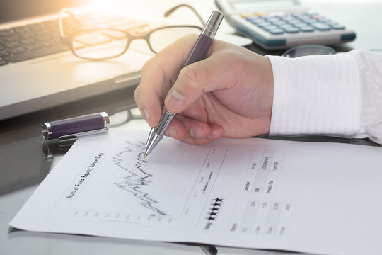 Businessman or fund manager review Mutual Fund information with performance line graph and benchmark with pen calculator and computer laptop.