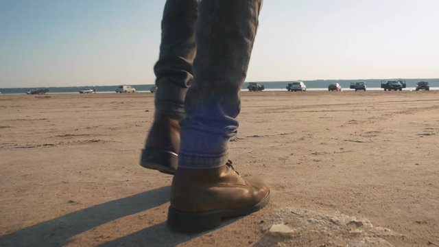 Close up shot of motorcyclist walking in desert with his helmet during sunset