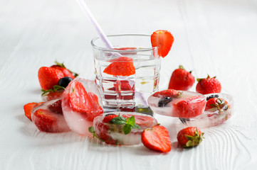Strawberry lemonade with ice in glass on wooden background