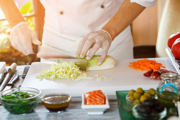 Hand with knife cuts cabbage. Cooking board and food ingredients. Best chef in town. Every detail matters.
