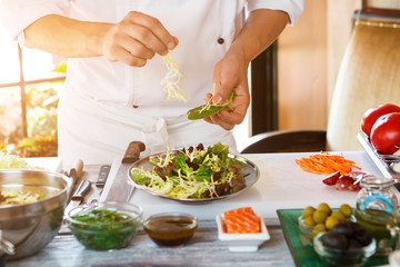 Male hands make salad. Salad plate on cooking board. Don't distract the cook. Need more ingredients.