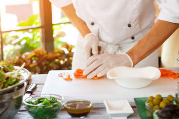 Man's hands touch raw fish. White bowl on cooking board. Chef of top class restaurant. Cook prepares special meal.