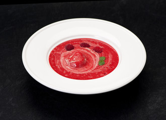 Cold dessert with raspberries and strawberries in a bowl on a black background