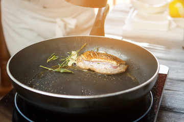 Spice falling on meat. Piece of meat on pan. Duck breast with pepper. Dish is almost ready.